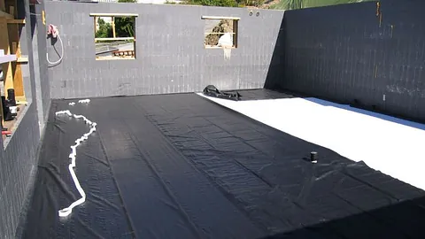 Isolert grunnmur med svart og hvit fuktsperre klargjort for videre bygging.