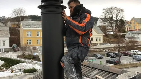 Flislegger påfører flislim med tannsparkel før legging av gulvfliser.